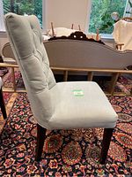 Side view of light blue upholstered chair showing tufted button backrest and dark wooden legs