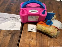 Electric balloon pump with balloons and accessories laid out on table next to instruction manual