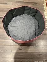 Photo showing the open foldable pink and gray kids ball pit set up on a wooden floor.