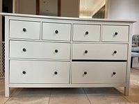 Front view of the Ikea Hemnes 8-drawer white stained dresser, showing all drawers closed except one slightly open on the right side, missing wood bar between right drawers.