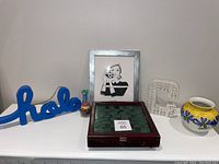 Full view of display showing all items together including the chess game, framed artwork, hola sign, decorative letter and vase.