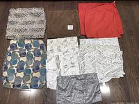 Grouped pillow case covers on floor including solid colors, prints, and white/silver Urban Barn pillow covers.