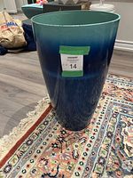 Image showing the tall, tapered plastic planter pot with green-to-blue gradient finish, placed on a patterned rug.