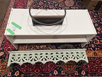 White wall shelf with back support panel and white shoe rack with decorative front panel on patterned carpet.