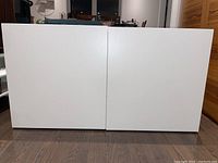 Front view of a white 2-door TV stand with clean flat doors and no handles.