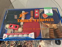 Photo of the vintage table tennis set in original box showing four paddles, package of balls, and net.