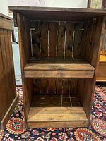 Front view of one dark wood cabinet showing the slatted sides and back with an open front and middle shelf.