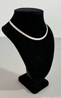 Necklace draped on black display bust showing full chain length and style