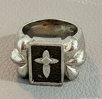 Front view of 925 silver ring showing rectangular face with raised fleur-de-lis on black background and fleur-de-lis designs on the sides.
