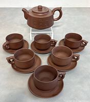 Complete tea set displayed with teapot, six cups, and matching saucers arranged on a surface.