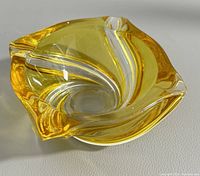 Photo of the ashtray showing its three-sided curved form, amber yellow glass with white and clear swirl detailing.