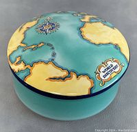 Top view of porcelain world map box lid with 'World Discovery' scroll detail and compass rose.