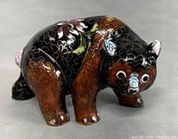 Front and side view of the black enamel cloisonne bear figurine with floral patterns in gold, brown, blue, and green.