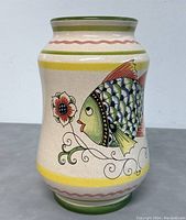 Front view of vintage Deruta ceramic vase with hand-painted colorful fish and floral design on a cream background with green rim.