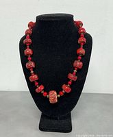 Front view of the vintage red coral necklace displayed on a black bust.