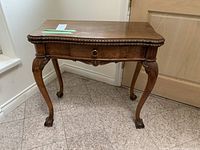 Front view showing carved apron, drawer front with round pull, cabriole legs and claw-and-ball feet