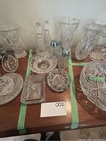 Overview of the crystal lot including bowl, candy jar, decanters in tray, footed bowl, honey dispenser, ashtray and tray.