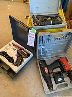 Overall view of all three tool kits including Dremel rotary tool, cordless drill in case, and Weller soldering gun in foam case on floor.