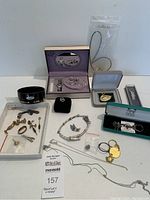 Overview photo showing a variety of jewelry pieces including necklaces, rings, cufflinks, pins, and jewelry cases along with a black bowl with 24KT gold trim.