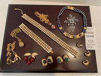 Full lot laid out on a dark wood display board showing all jewelry pieces including necklaces, rings, brooch, earrings, and bracelets.