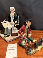 Both figurines together on wooden surface against black background