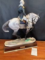 Full side view of the porcelain figurine showing rider, horse, and wood base