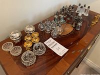 Overview of assorted salt and pepper shakers and small serving bowls arranged on a wooden surface, showcasing variety in materials and styles.