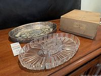 Photo of the silver plated oval serving tray with detailed grapevine pattern and the oval glass hors d'oeuvre dish placed on a wooden table.