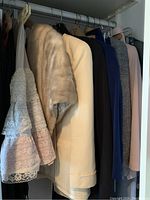 Fur shawl and multiple suits hanging in closet