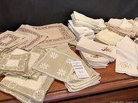 Overview of assorted napkins on a table showing multiple stacks and styles including embroidered and crocheted edges