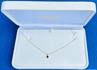 10K solid gold box chain necklace with garnet pendant displayed inside a white clam shell box with padded interior.