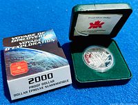 2000 Canadian Voyage of Discovery proof silver dollar coin with original box, case, and certificate seen on blue background.
