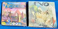 View of two board games side by side showing front cover art. Left game is 7 Wonders featuring ancient classical architecture and statues, right game is EVO with dinosaur illustrations.