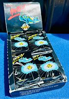 Photo showing open booster box containing multiple sealed booster packs of Indy Car trading cards with black packaging and blue Indy Car images.