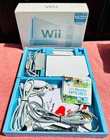 Full overview of the lot contents neatly packed in original Wii box showing console, cables, controllers, and Wii Sports game