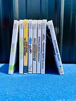 Photo showing 9 Nintendo Wii game cases upright side by side, titles visible on spine labels including Super Mario Galaxy, Pokemon Revolution, Soul Calibur, and others.