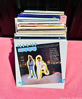 A collection of vinyl albums with Miami Vice soundtrack in front, showing colorful 80s style cover art with two figures and night cityscape.