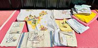 Full assortment of vintage linens showing various colorful designs laid out on a red surface.