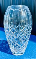Full view of clear Waterford Crystal flower vase showing detailed cut glass design on an oval-shaped body, on blue felt background.