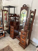 Perspective view showing entire antique dresser vanity with back mirror and hinged side mirrors in storage area.