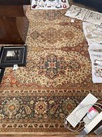 Full view of large rug laid on hardwood floor with jewelry and framed art on top