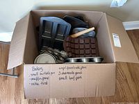 Open box showing various baking pans and Wilton silicone candy mold, wooden rolling pin