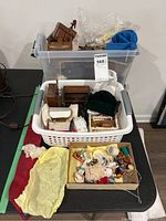 Overall view of boxes and baskets containing wood dollhouse furniture, mini accessories, and fabric pieces including a large blue tie.