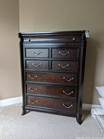 Front view of tall six drawer chest showing dark wood finish and drawer handles.