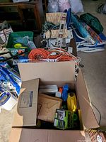 Overview of assorted cords, level, and other tools inside cardboard boxes on the floor.