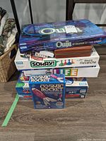Stack of board game boxes including Ouija, Sorry!, The Game of Life, Cosmic Rocket and Backgammon case visible at bottom
