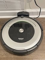 Top view of iRobot Roomba 690 vacuum cleaner placed on charging dock with visible dust and surface wear.