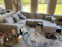 Full view of the assembled four-piece modular sofa set arranged in corner shape with throw pillows and cushions, situated in living room near large windows.