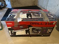 Original box for Thermos Grill2Go portable grill with taped and worn condition. Includes promotional images showing grill and cooking surface with Teflon coating.