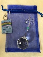 Overview of the crystal art hanging decor showing the turquoise bead and large crystal teardrop with attached blue organza pouch.
